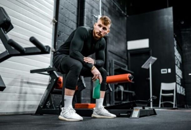 Treneris Mindaugas atlieka cardio treniruotę, geria vandenį apie mus